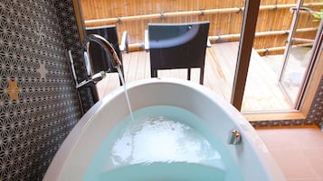 Relax in a spa-like setting with a bathtub and enjoy a view of lush greenery from the large window.