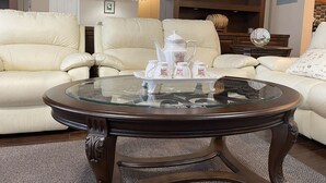 A living room with two cream-colored sofas, a glass coffee table, and a decorative tray with teapots and cups. - Chinese style suite near golf course (Surrey)