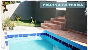 An outdoor swimming pool with blue tiles, surrounded by a small garden and steps leading up to a covered area. - Hospedaria Oca Ruca (Guarapari)