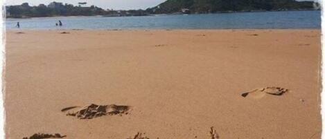 Una playa con huellas en la arena formando la palabra "Setibó".
