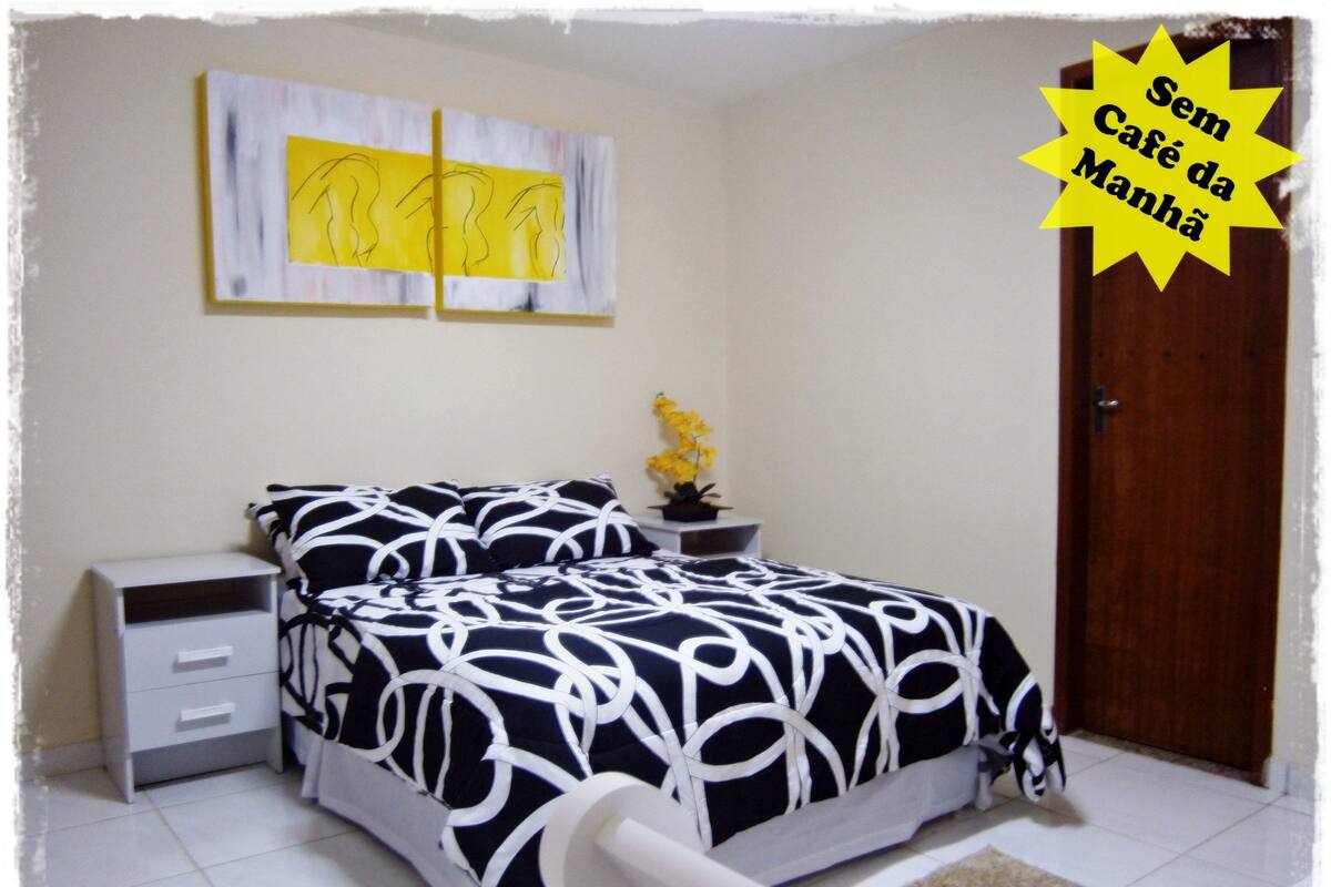 A bedroom with a bed, bedside tables, a nightstand, a potted plant, and a door.
