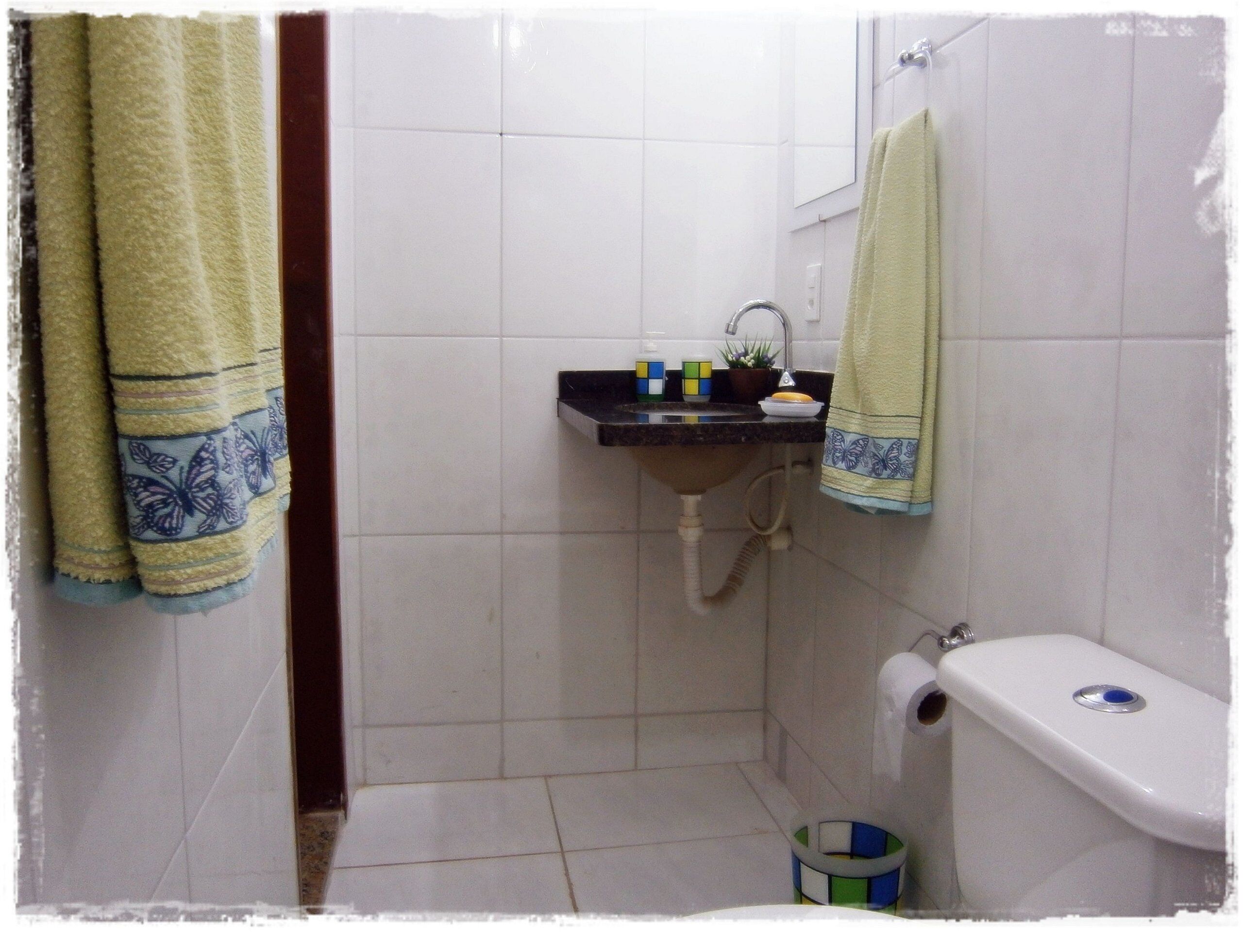Une petite salle de bain avec un lavabo, des toilettes et un miroir. Deux serviettes sont accrochées au mur.