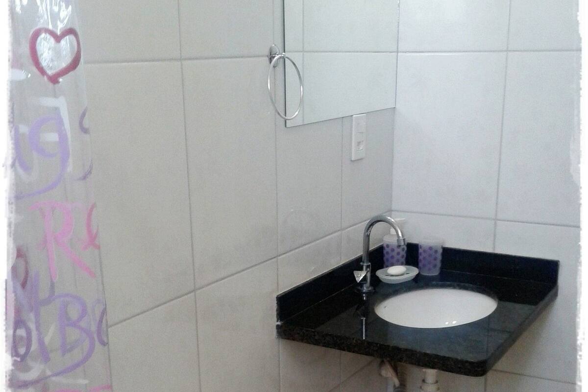 A small bathroom with a toilet, a sink, and a shower curtain with heart designs.
