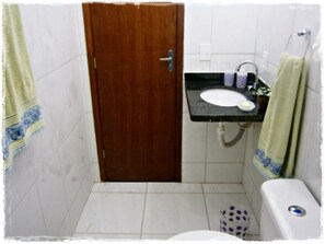 Bathroom features a sink, toilet, and trash bin, with towels hanging on the wall.