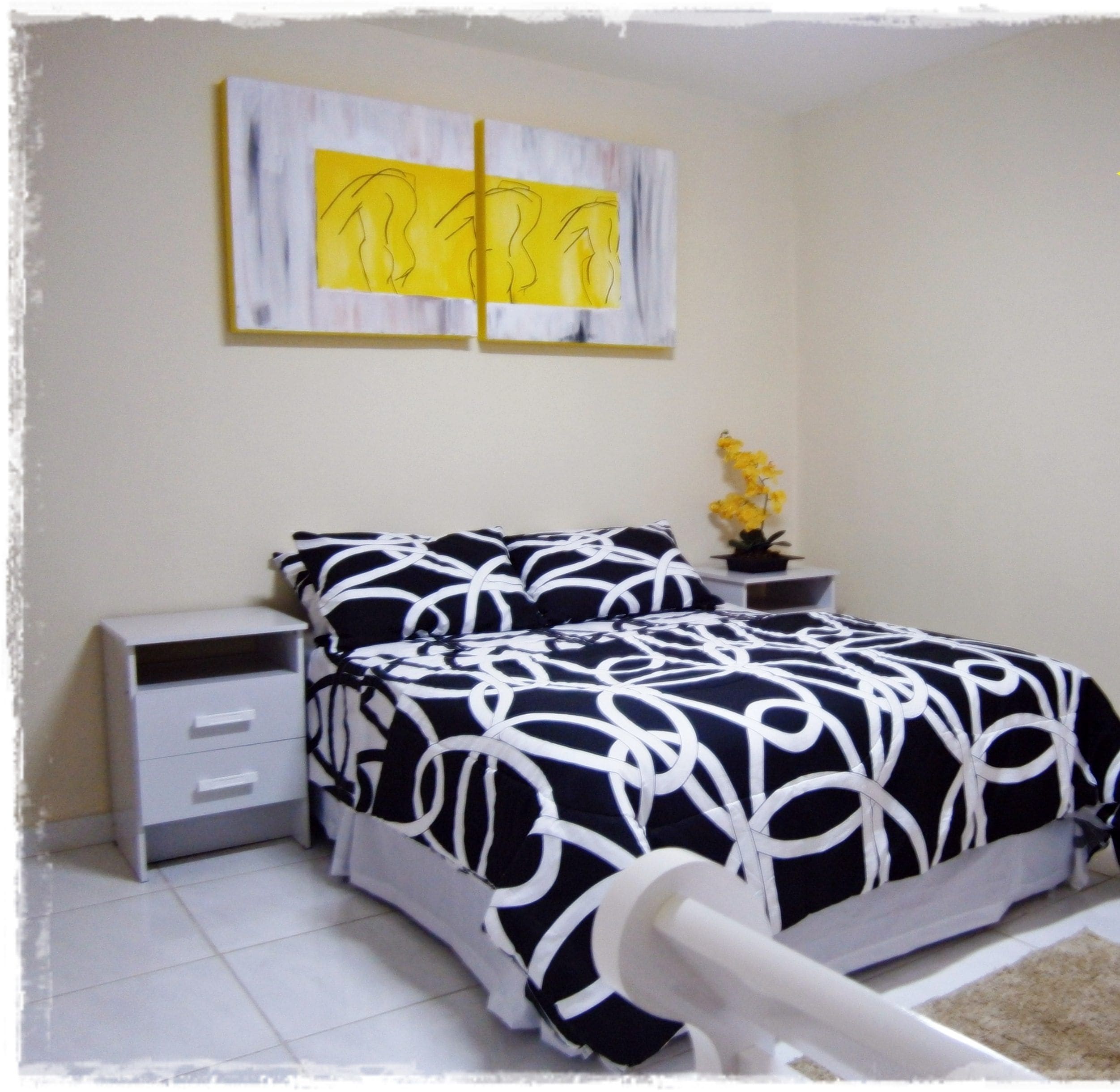 A bedroom with a bed, bedside tables, a nightstand, a potted plant, and a door.