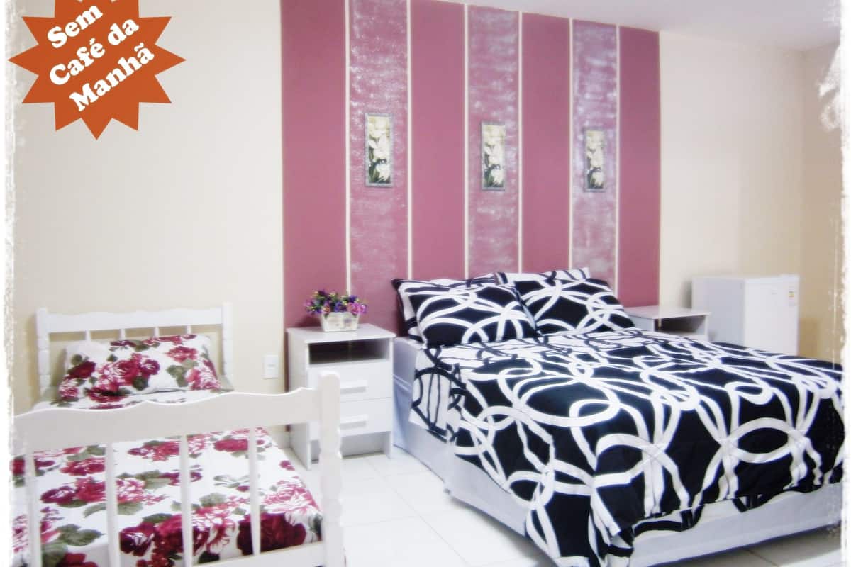 A bedroom with a bed, a nightstand, a chair, and a small table.