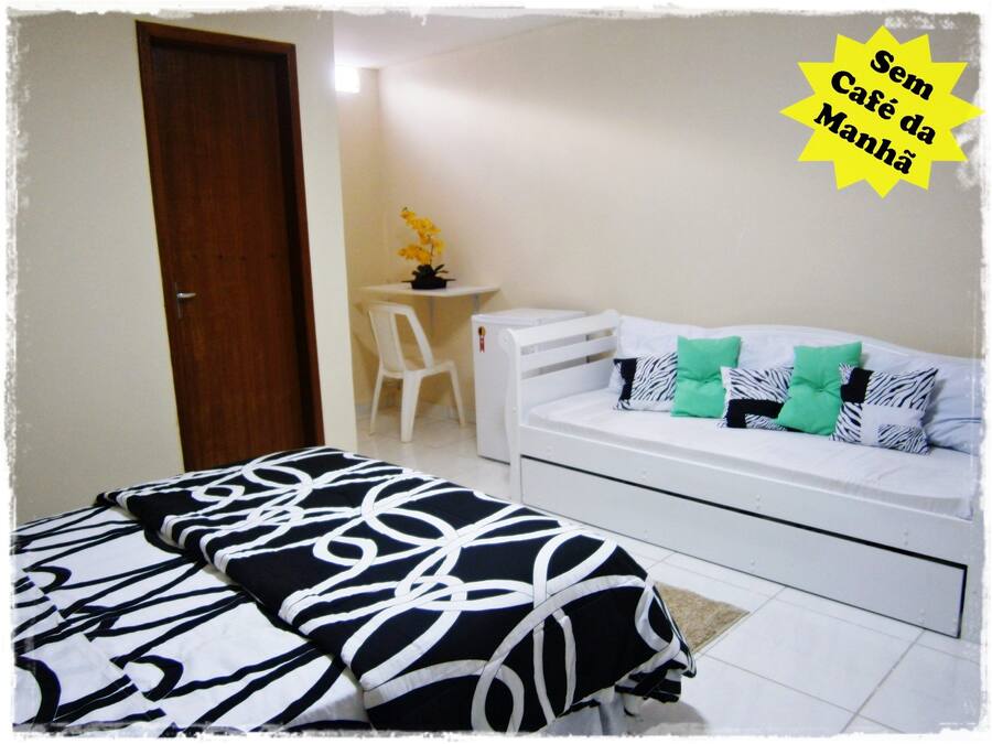 Un dormitorio con una cama, un sofá blanco y una pequeña mesa con una planta.