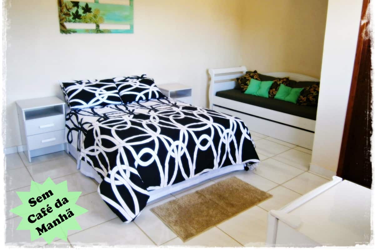 A bedroom with a bed, a nightstand, a sofa, and a small table.