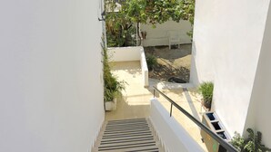 A staircase leading to a balcony with potted plants and a white wall. - Renovated 2-Bed Gem in Kassiopi's Vibrant Tourist Village, WiFi, Terrace (Kassiopi)
