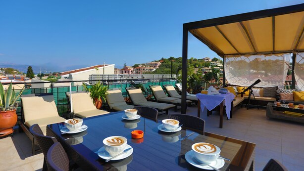 A rooftop terrace with outdoor seating, a table with coffee cups, and a view of the cityscape. - Renovated 2-Bed Gem in Kassiopi's Vibrant Tourist Village, WiFi, Terrace (Kassiopi)