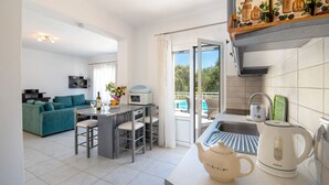 A modern kitchen with a kettle, a microwave, and a dining area with a table and chairs. - Stylish Hideaway, 2-mins from Marmari Beach! (Loggos)