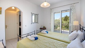 A bedroom with two beds, a balcony, and a view of greenery. - Stylish Hideaway, 2-mins from Marmari Beach! (Loggos)