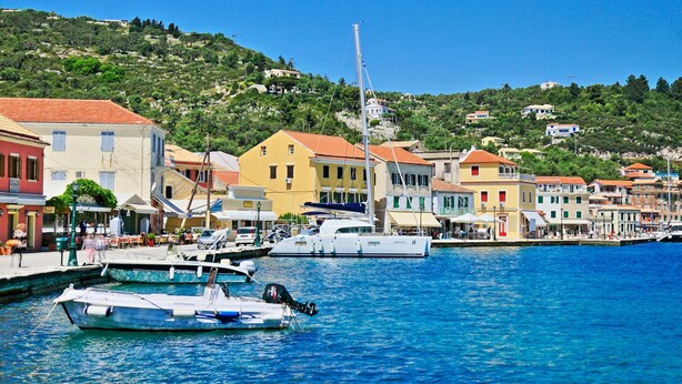 A coastal town with colorful buildings, a marina with boats, and a hill in the background. - Stylish Hideaway, 2-mins from Marmari Beach! (Loggos)
