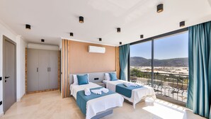 Une chambre d’hôtel moderne avec deux lits, un balcon offrant une vue agréable et une grande fenêtre.