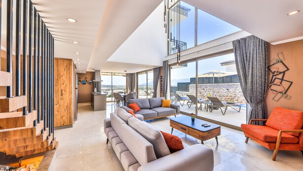 Un vaste espace de vie comprenant un grand canapé, une table basse et une table à manger. Un balcon avec des sièges d’extérieur offre une vue sur la ville.