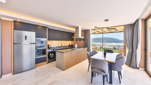 Une cuisine moderne dotée d’un four encastré, d’un réfrigérateur en acier inoxydable et d’un coin repas avec une table et des chaises.
