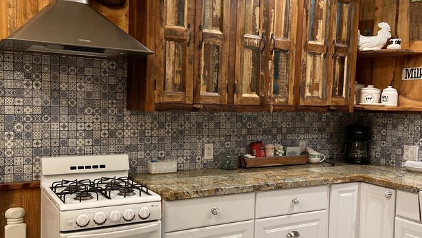 A kitchen with wooden cabinets, a gas stove, and patterned tile flooring. - Pacific Coast Highway Milkhouse (San Luis Obispo)