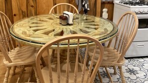A wooden interior with a round glass table surrounded by wooden chairs, a white stove, and a fire extinguisher mounted on the wall. - Pacific Coast Highway Milkhouse (San Luis Obispo)
