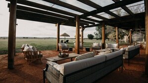 An outdoor seating area with wicker furniture and a view of a field. - Bullo River Station (Baines)