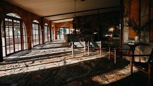 A spacious room with a stone floor, large arched windows, and a ceiling fan. - Bullo River Station (Baines)