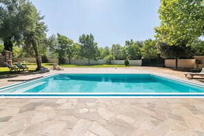 A rectangular swimming pool with a stone patio in the foreground. - Estate Villa OINOI with Pool  (Marathon)