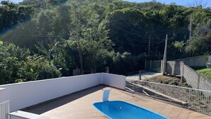 A rooftop pool with a wooden deck and a white railing. - Casa de Praia e Campo com Piscina (Garopaba)