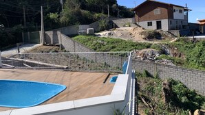 A residential area with a swimming pool, a wooden deck, and a house under construction. - Casa de Praia e Campo com Piscina (Garopaba)