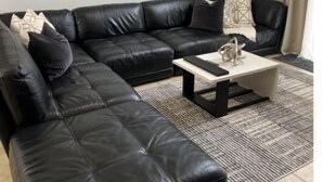 A modern living room with a black leather sectional sofa, a coffee table, and a large abstract painting on the wall. - Luxury 5bd home close to Disney parks private gated property  (Kissimmee)