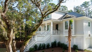 A two-story house with a white exterior, a front porch, and a staircase leading to the second floor.