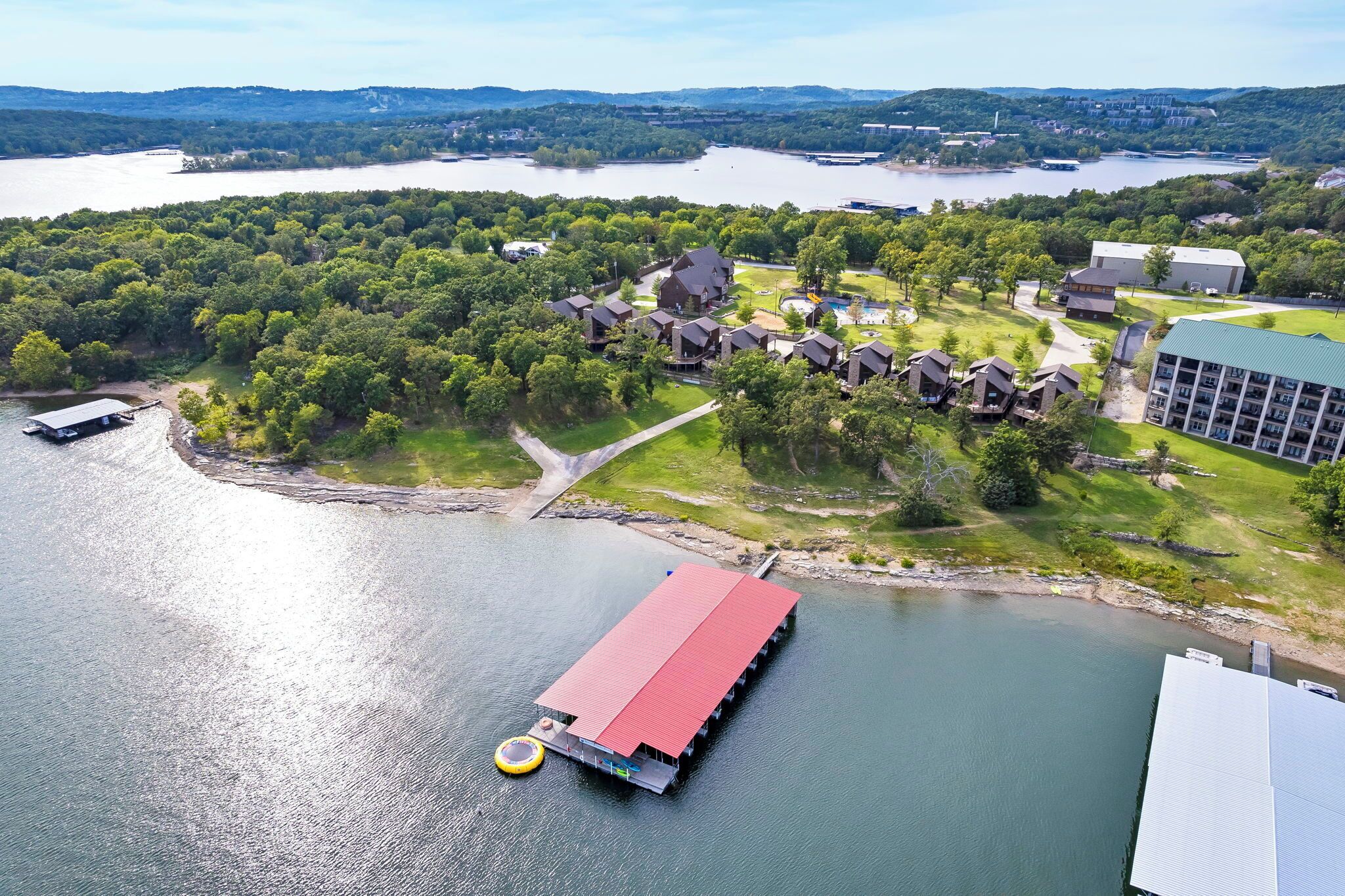 A lakeside property with a dock, a swimming pool, and a large building with multiple floors.