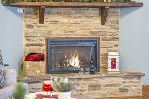A stone fireplace with a glass door, a basket with a red blanket, and a small white lantern.