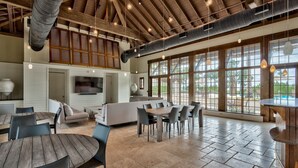 Un vaste espace intérieur doté d’un haut plafond, de grandes fenêtres et d’un agencement varié comprenant des tables et des chaises.