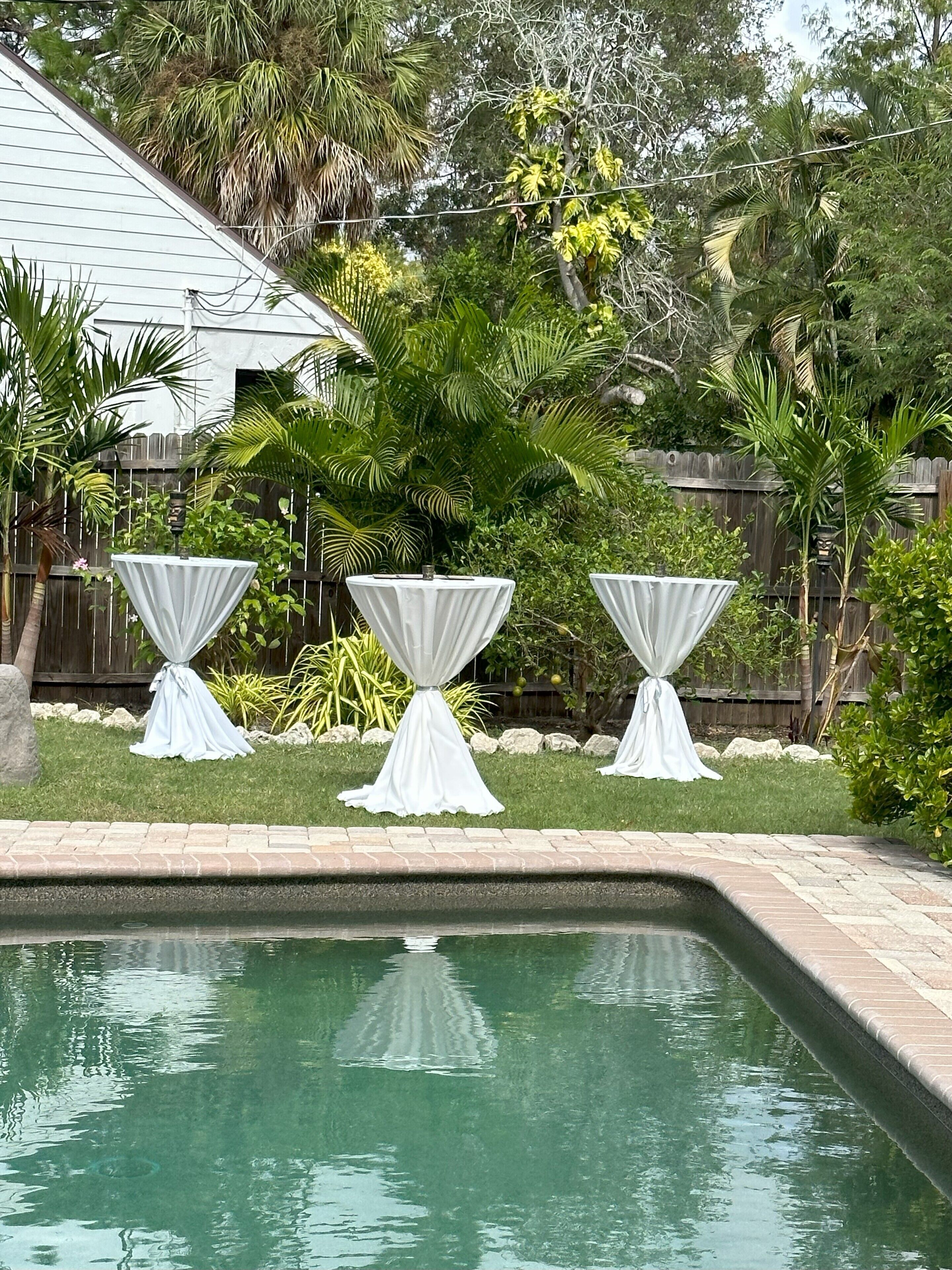 Une piscine avec trois tables abritées et une clôture en bois en arrière-plan.