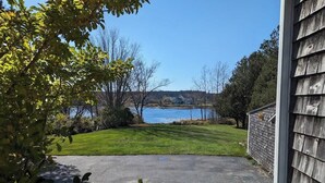 A view of a lake from a driveway with a wooden building on the right. - Beachfront Cottage with Fire Pit in Watering Cove (Gouldsboro)