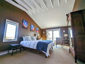 A bedroom with a bed, two windows, a chair, a dresser, and a ceiling with a wavy design. - Oceanfront Cottage w/ Fire Pit & Sunset Deck (Gouldsboro)