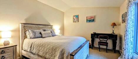Een slaapkamer met een bed, een bureau, een stoel en een lamp.
