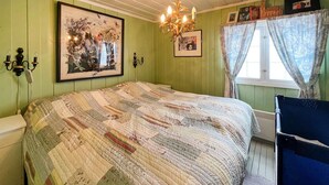Un dormitorio con una cama grande, una araña, una ventana con cortinas y un teléfono instalado en la pared.