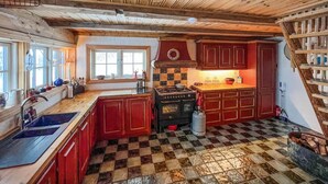 Una cocina con piso a cuadros, armarios de madera, una estufa y una ventana.