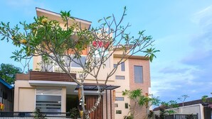 A modern two-story house with a flat roof, a large tree in the front yard, and a gated entrance. - Jepun Guest House (Mataram)