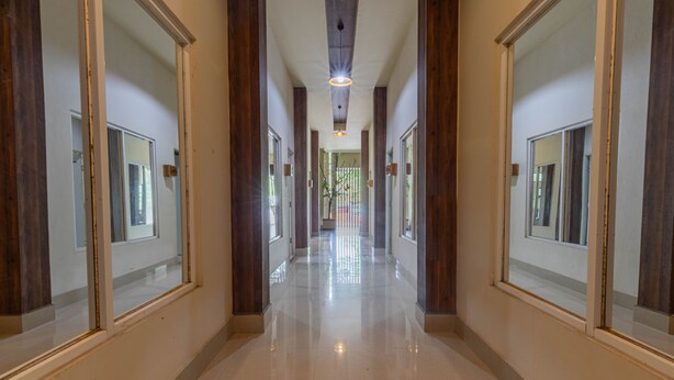 A long, polished hallway with wooden paneling and large mirrors on either side. - Jepun Guest House (Mataram)
