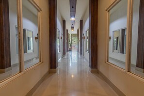 A long, polished hallway with wooden paneling and large mirrors on either side. - Jepun Guest House (Mataram)