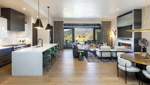 Una cocina moderna con una isla central, un comedor con mesa redonda y una sala de estar con chimenea.