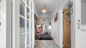 A hallway with patterned floor tiles, a wooden door, and a wall-mounted light fixture. - Worldwide Backpackers Limited (Wellington)
