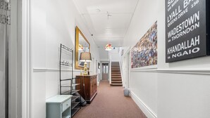 A hallway with a light blue desk, a mirror, a lamp, and a staircase leading to another floor. - Worldwide Backpackers Limited (Wellington)