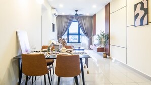 A dining area with a table set for two, a ceiling fan, and a view of the outdoors through large windows.
