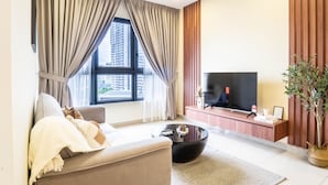 A modern living room with a sofa, coffee table, TV, and curtains.