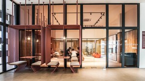 A modern interior with a central seating area, large windows, and a visible sign for a co-working space.