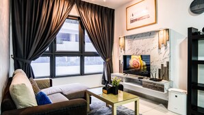 A modern living room with a sofa, a glass coffee table, a fireplace, and a TV.