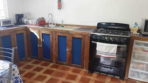 Une cuisine avec des meubles de rangement en bois, une cuisinière, un évier et un grille-pain.