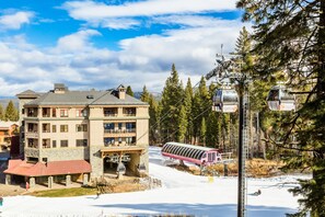 Un hotel de varios pisos con un telesilla y un paisaje cubierto de nieve.